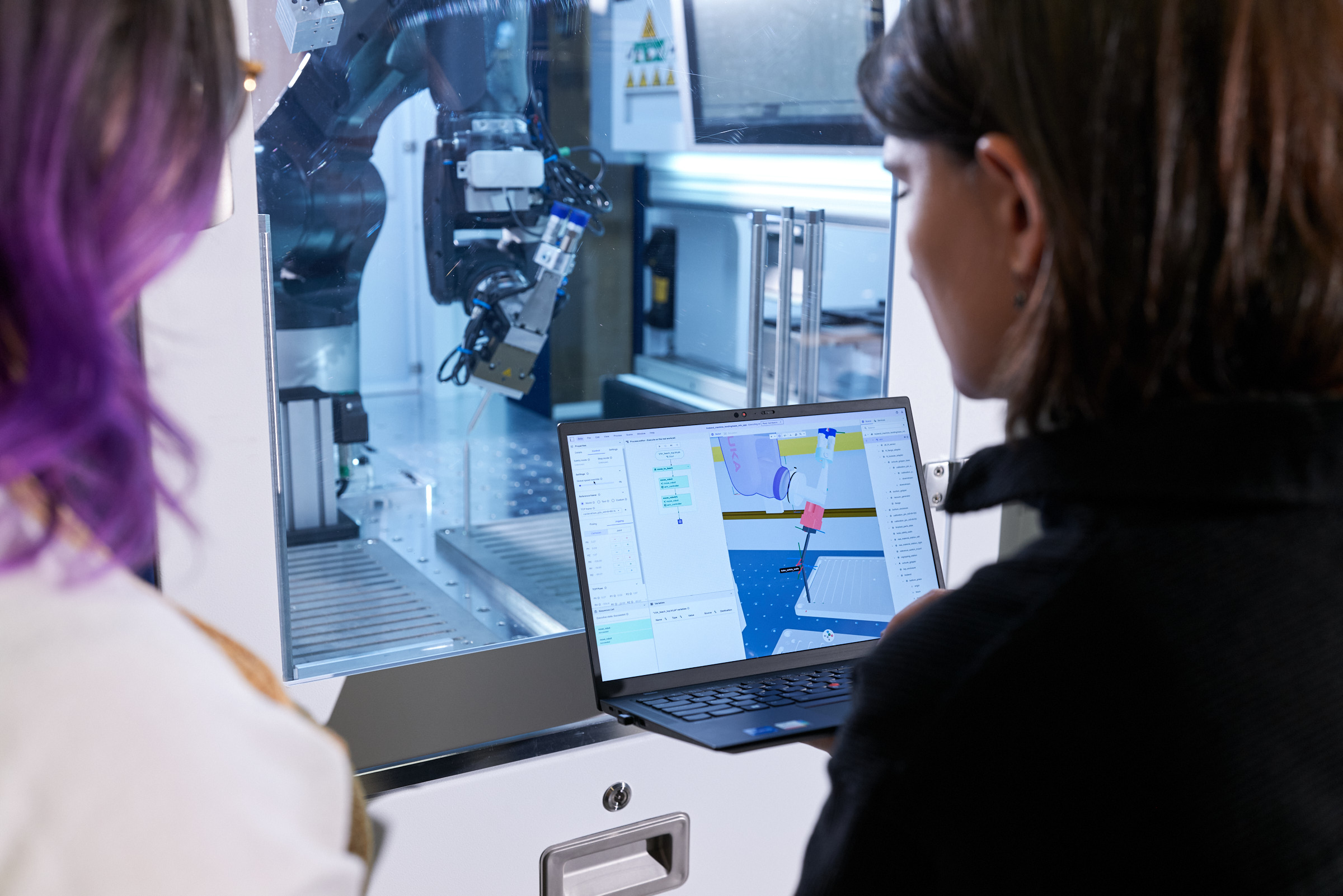 A monitor with Intrinsic Flowstate and a digital representation of a robot, with the real robot right behind the monitor.